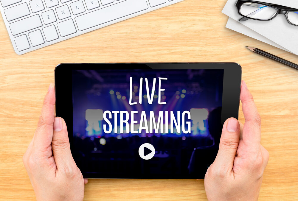 Hand holding tablet with Live Streaming word on wood table ,Internet marketing concept.